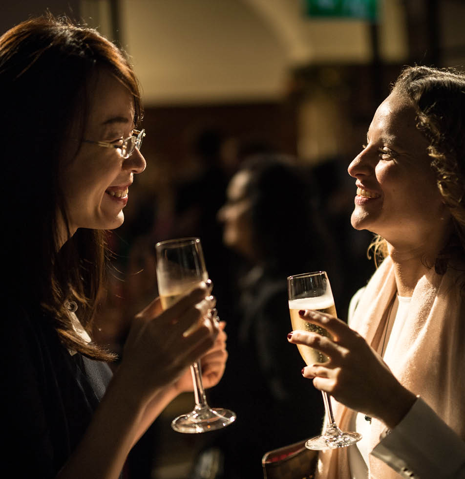 Two women smiling whilst holding a glass of champagne